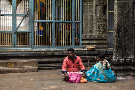 Kumbakonam, Tamil Nadu, India - February 2020: Indian pilgrims sitting on the stone floor of an illuminated hall inside the ancient Hindu temple of Swamimalai.のeditorial素材