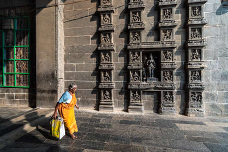 Chidambaram, Tamil Nadu. India - February 2020: An elderly Indian woman walks past the ornate carvings on the walls of the ancient Nataraja temple in Chidambaram.のeditorial素材
