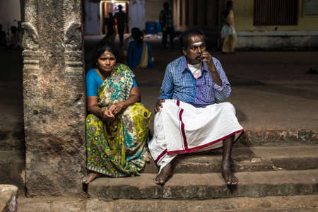 Kumbakonam, Tamil Nadu, India - February 2020: An Indian man and woman sitting on the stone steps of an ancient temple in Kumbakonam.のeditorial素材