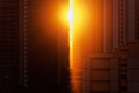 Evening golden hour sunlight streaming through skyscrapers in an urban cityscape of the suburb of Kandivali in the city of Mumbai.の写真素材