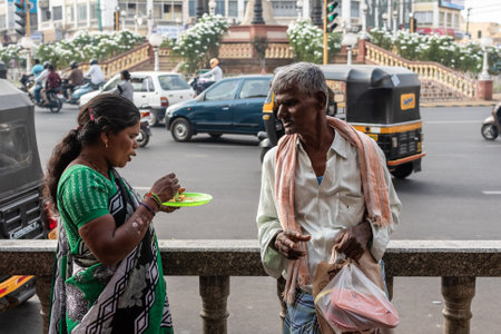 Mysuru, Karnataka, India - January 2019: An old man and a woman having a conversation on a busy street in the city of Mysore.のeditorial素材