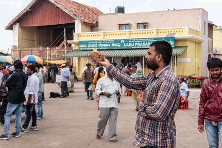 Mysuru, Karnataka, India - January 2019: A devout Hindu pilgrim performing a ritual with fire at the ancient Chamundeshwari temple in Chamundi Hills.のeditorial素材