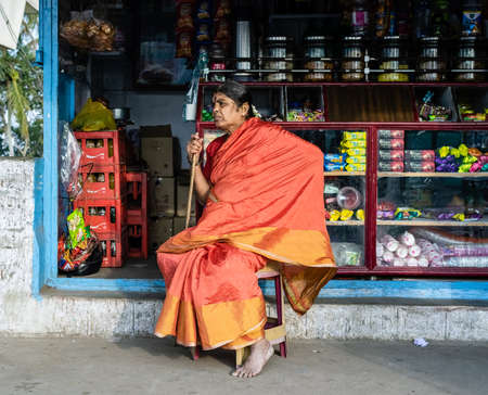 Mysuru, Karnataka, India - January 2019: An Indian woman shopkeeper sitting outside her grocery...