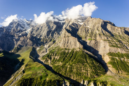 A Himalayan mountain face with green fields and meadows on its steep slopes off the town of Keylong in Lahaul in Himachal Pradesh, India.の写真素材