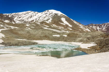 The partially frozen lake on top of the high altitude pass of Shingo La in the Great Himalayan range...