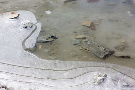 Top angle view of submerged rocks below the icy surface of a frozen lake near the Shingo La pass in the Himalayan region of Zanskar.の写真素材