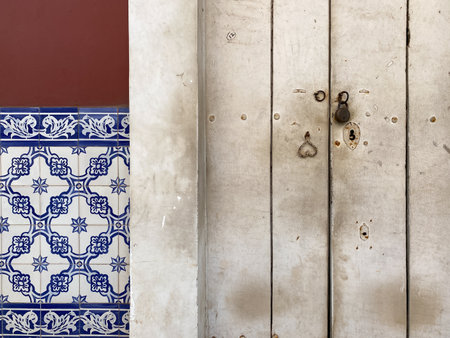 Abstract detail of an old rustic wooden door beside a wall with beautiful Portuguese era mosaic tiles in the city of Panjim in Goa.の写真素材