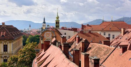 View of the old town center of Graz with the church Dreifaltigkeitskirche in the middle from the staircase of Castle Schlossberg Hill. Graz, Austria.の写真素材