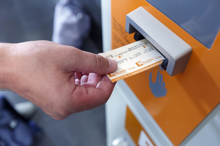 BARCELONA/ SPAIN - AUGUST 6, 2016: A man validating ticket in a punching machine for the train. Barcelona, Spain.のeditorial素材
