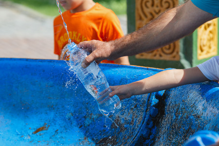 A Christian family pouring the holy water in a bottle from the Holy spring at the Sergiyev Posad monastery. Moscow region, Russia.のeditorial素材