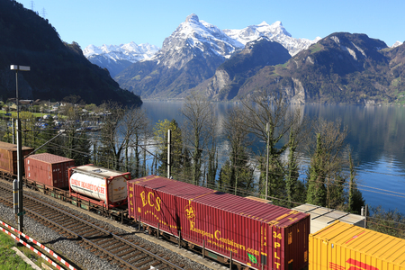 SISIKON, SWITZERLAND - APRIL 17, 2018. Freight train riding on the railway along the lake Lucerne near the town Sisikon. View of the Alps. Switzerland.のeditorial素材