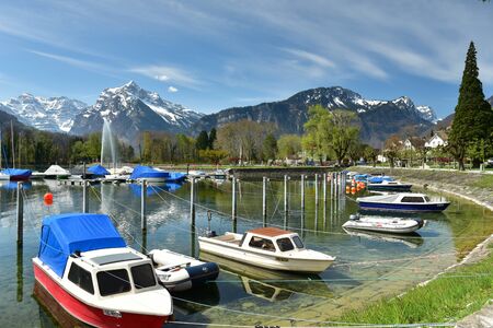 WEESEN, SWITZERLAND - APRIL 16, 2019. Boats moored on the Walensee lake on a sunny spring day. View of the snow-capped Alps. Village of Weesen, See-Gaster, canton of St. Gallen, Switzerland.のeditorial素材