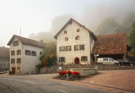 VILLIGEN, SWITZERLAND - OCTOBER 19, 2018. Old residential neighborhood on a foggy autumn day. View of the ancient fontain. Town of Villigen, district of Brugg, canton of Aargau, Switzerland, Europe.のeditorial素材