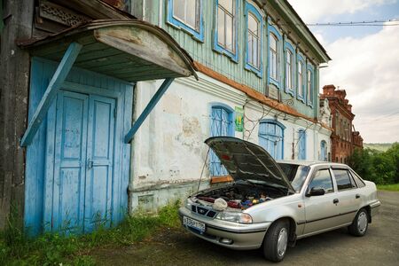 VISIM, RUSSIA - JUNE 27, 2015. Modern car with an open hood parked in front of the historical building. Village of Visim, Sverdlovsk region, Urals, Russiaのeditorial素材