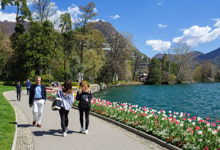 LUGANO, SWITZERLAND - APRIL 17, 2018. People walking in the Park Ciani at the lake Lugano on a spring sunny day. View of the blooming tulips. City of Lugano, canton of Ticino, Switzerland, Europe.のeditorial素材