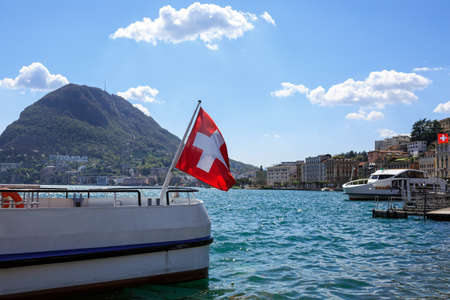 City of Lugano at the lake Lugano on a spring sunny day. View of a ship decorated with the Swiss flag. Lugano, canton of Ticino, Switzerland, Europe.の写真素材