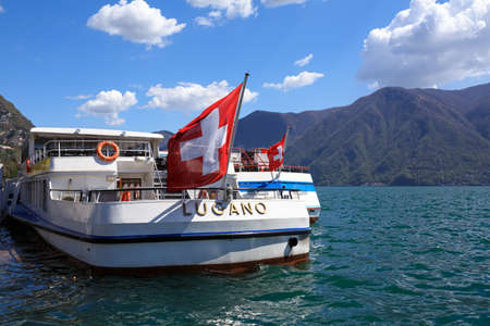 LUGANO, SWITZERLAND - APRIL 17, 2018. Lake Lugano on a spring sunny day. View of a passenger ship decorated with the Swiss flag. Lugano, canton of Ticino, Switzerland, Europe.のeditorial素材