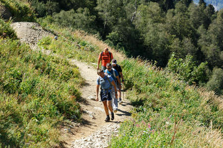 KRASNAYA POLYANA, RUSSIA - AUGUST 27, 2020. Group of hikers walking on a mountain trail in Caucasian mountain range. Adler District of Sochi, Krasnodar region, Russia.のeditorial素材