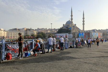 ISTANBUL, TURKEY - OCTOBER 06, 2020. Galata Bridge with the New Valide Sultan Mosque in the background. Fishermen with fishing rods fishing from the bridge. City of Istanbul, Turkey.のeditorial素材