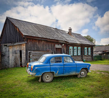 VISIM, RUSSIA - JUNE 25, 2015. Russian village in summer. Vintage car Moskvich 403 in front of old wooden residential house. Ust-Utka village, Nizhny Tagil City District, Sverdlovsk Olbast, Russia.のeditorial素材