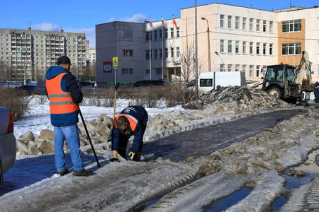 BALASHIKHA, RUSSIA - MARCH 19, 2021. Two workers of the municipal service clean the road from the ice. View of the school N 27. City of Balashikha, Moscow region, Russia.のeditorial素材
