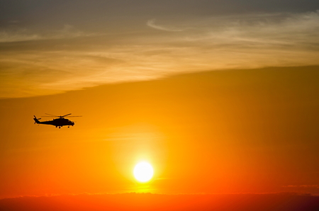 silhouette of a flying helicopter at sunsetの写真素材