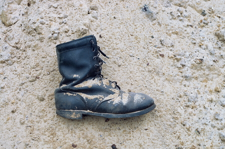 worn leather military boots on the sand