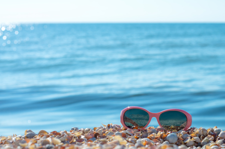 baby pink sun-glasses on the background of the sea horizon with the sun.の写真素材