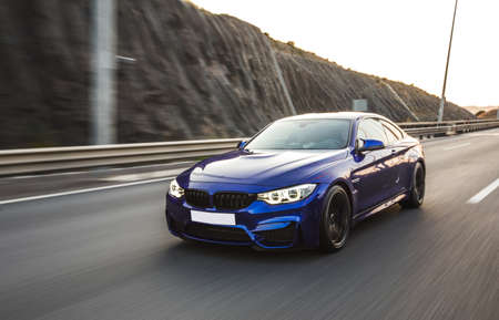 Blue luxury sport coupe on the road. front view