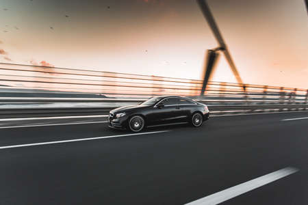 Black sedan driving over the bridgeの写真素材