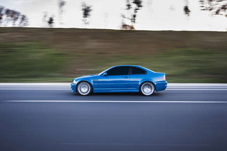 Blue sedan driving on the highway in the dusk timeの写真素材
