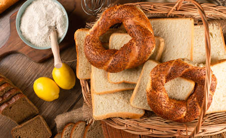 Bagels and slices of white bread in basket with flour