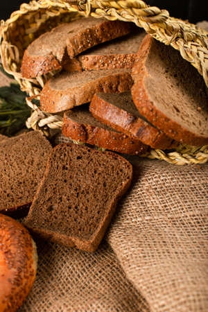 Bagel and slices of dark bread in basket on tablecloth