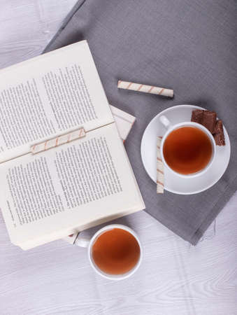 Book, Sweet snacks and cup of tea on the table