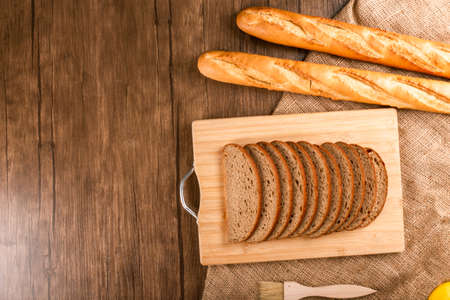 Slices of bread and french baguette on tableclothの写真素材