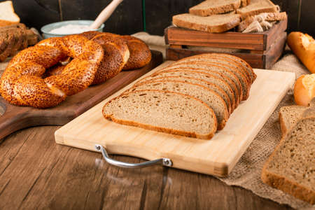 Tasty bagel with slices of bread on kitchen board