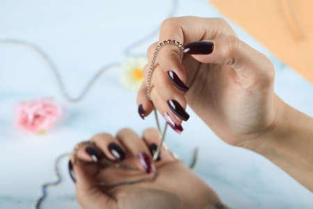 Well manicured, red nail polished woman hands holding a necklace