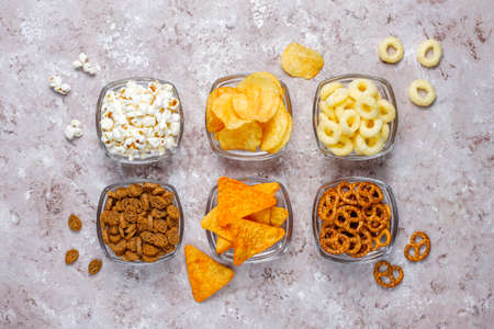 Salty snacks. Pretzels, chips, crackers,popcorn in bowls. Unhealthy products. food bad for figure, skin, heart and teeth. Assortment of fast carbohydrates foodの写真素材