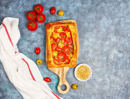 Delicious homemade rustic open pie ,palette with various tomatoes and pine nuts,top viewの写真素材