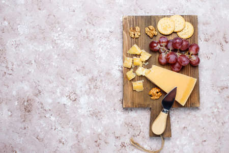 cheese board with hard cheese ,cheese knife,red wine glass,grape on brown concrete backgroundの写真素材