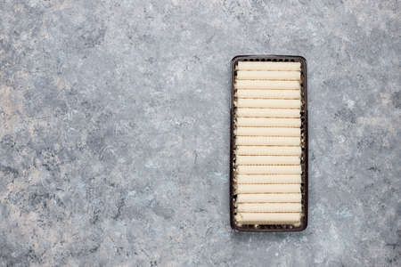 Plate with tasty wafer roll sticks on concrete background, top view. Crispy foodの写真素材
