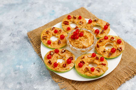 Healthy sandwich. Green apple rounds with peanut butter and red currant and pecan nuts on grey concrete background,top viewの写真素材