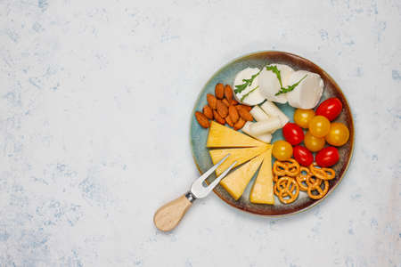 Various cheese and cheese plate on light table with different nuts and fruitsの写真素材