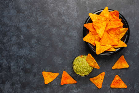 Fresh homemade hot guacamole sauce with nachos on dark background,top viewの写真素材