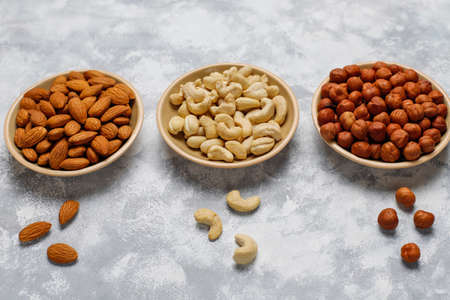 Assortment of nuts in ceramic plates. Cashew, hazelnuts, walnuts, pistachio, pecans, pine nuts, peanut, raisins.top viewの写真素材