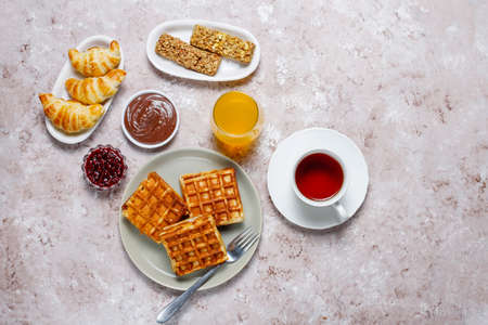 Delicious breakfast with coffee, orange juice, waffles,croissants,jam,nut paste on light background,top viewの写真素材