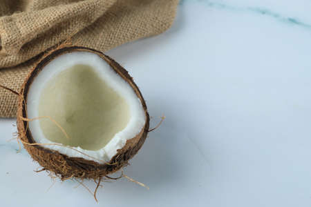 Half broken coconut fruit on a marble on a piece of burlap