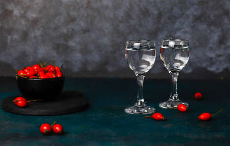 Alcoholic drink vodka in glasswith rosehips on dark backgroundの写真素材