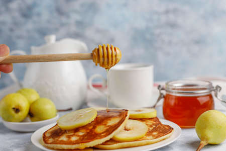 Homemade breakfast: american style pancakes served with pears and honey with a cup of tea on concrete background. Top view and copy spaceの写真素材