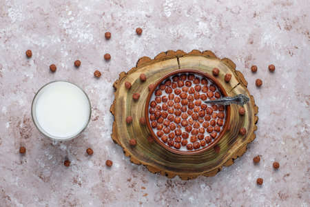 Bowl with chocolate balls and milk on light background,top view